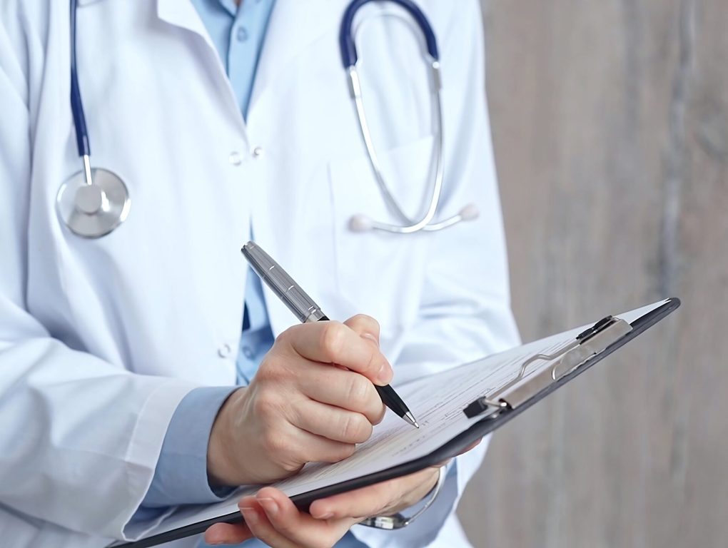 Healthcare professional doctor writing medical records on a clipboard. Female unrecognizable physician at work. Medicine and pharmacy.